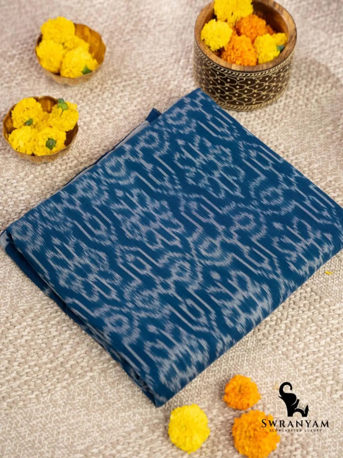 Folded handwoven indigo blue cotton ikat saree showing traditional white ikat motifs on the body