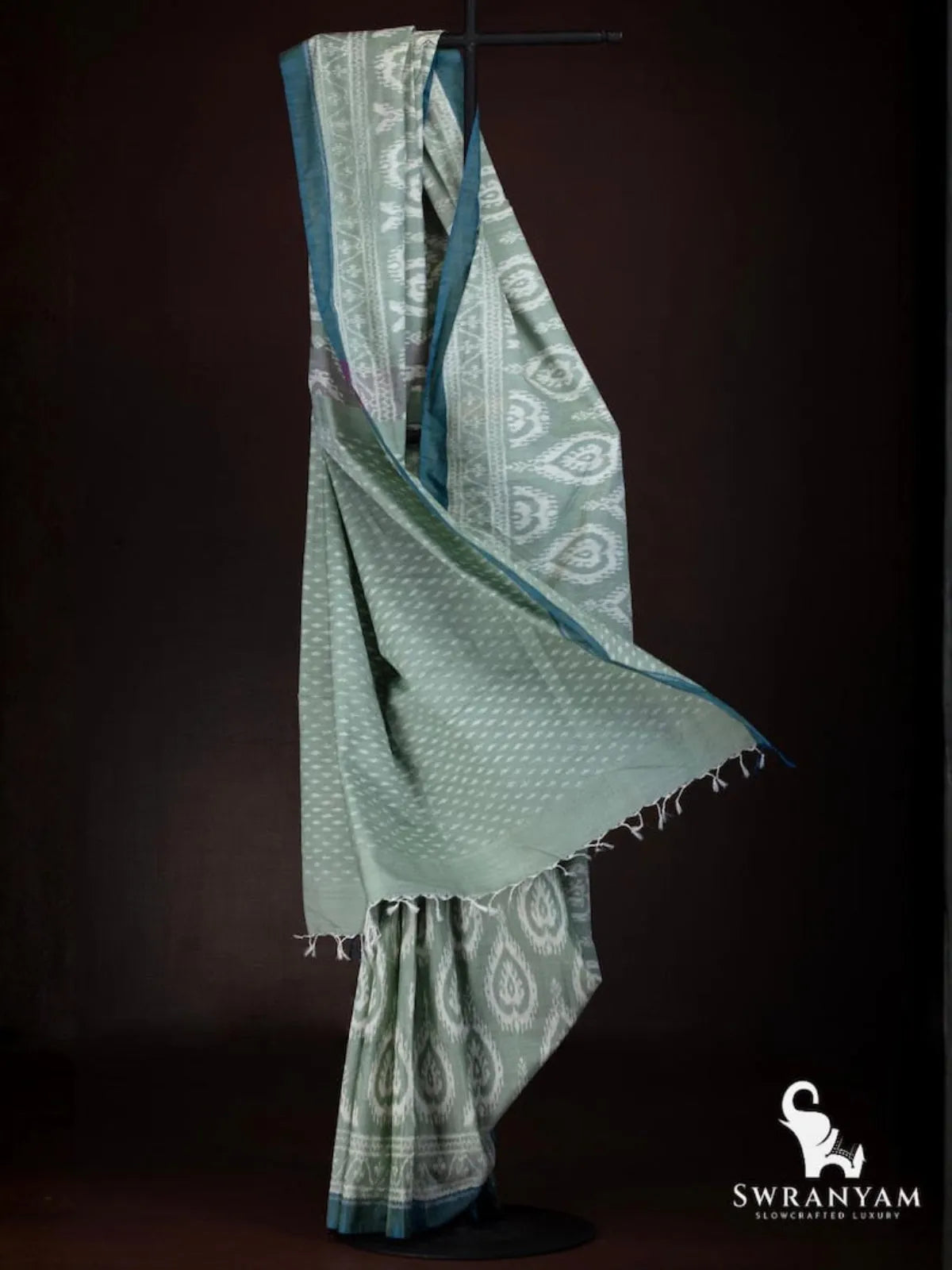 Flowing drape of sage green weft ikat saree showing dotted ikat body and heart paisley motif pleats
