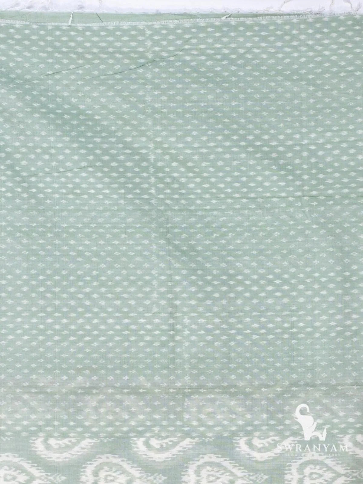 Close up of white dotted weft ikat weave on sage green silk cotton saree body