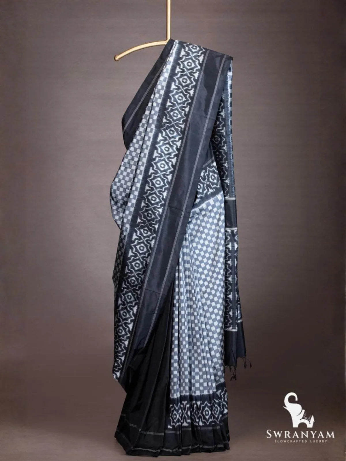 Black and grey Pochampally ikat silk saree with checker body and geometric ikat border draped on a hanger