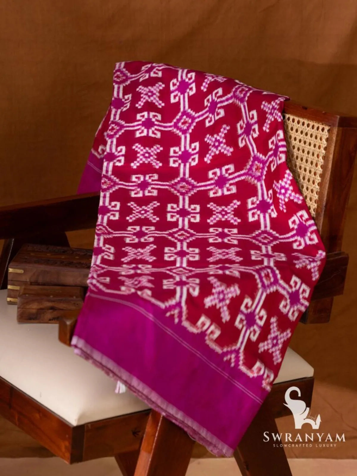 Crimson red Telia Rumal double ikat silk saree with white and magenta geometric motifs and magenta border folded on chair