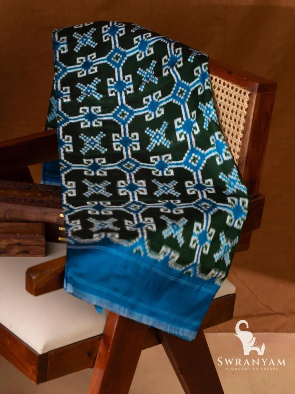 Bottle green Telia Rumal double ikat silk saree with blue and white geometric motifs and blue border folded on chair