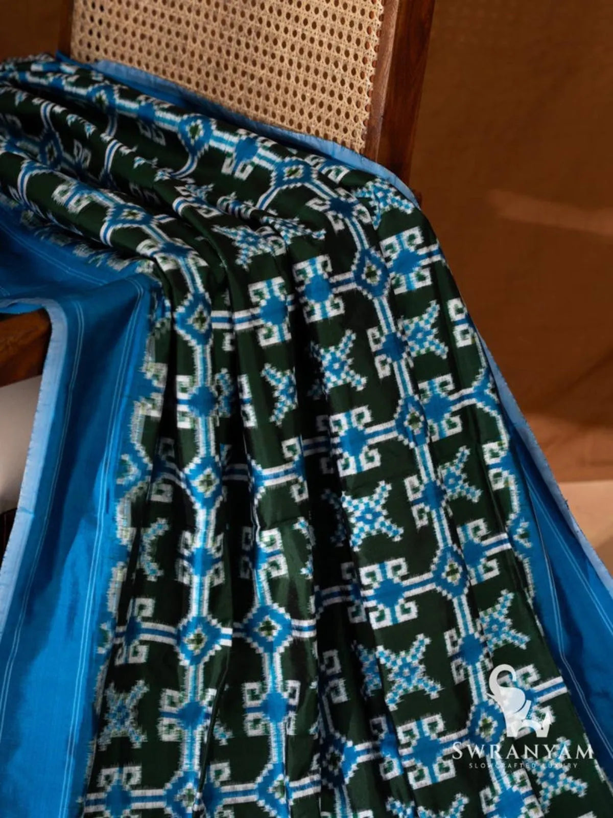 Bottle green Telia Rumal silk saree pleats with blue and white double ikat motifs beside blue border