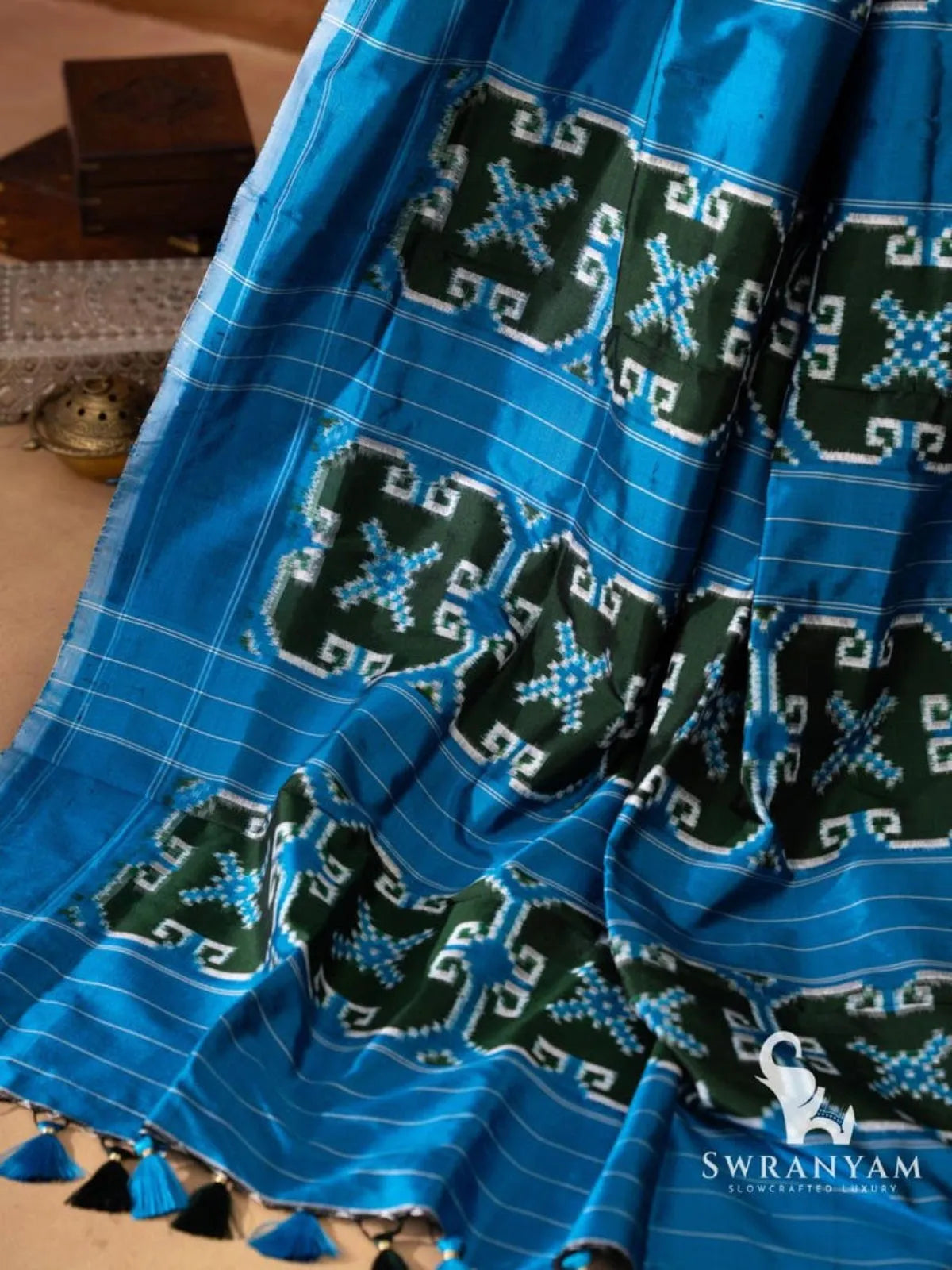 Blue pallu with rows of green ikat motif panels and blue and black tassels on Pochampally double ikat silk saree