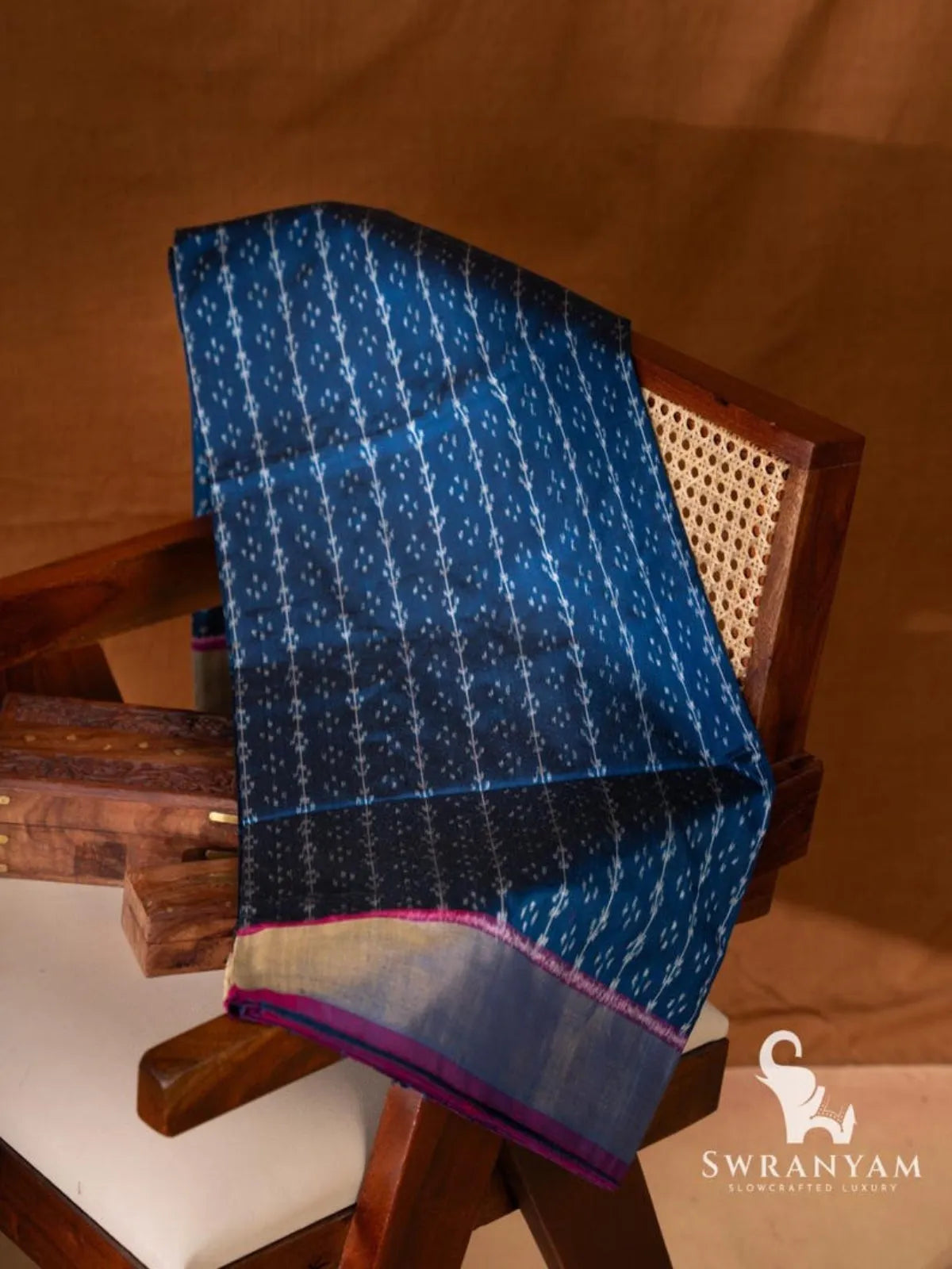 Indigo blue Pochampally single ikat silk saree with white ikat vine motifs and zari border folded on wooden chair