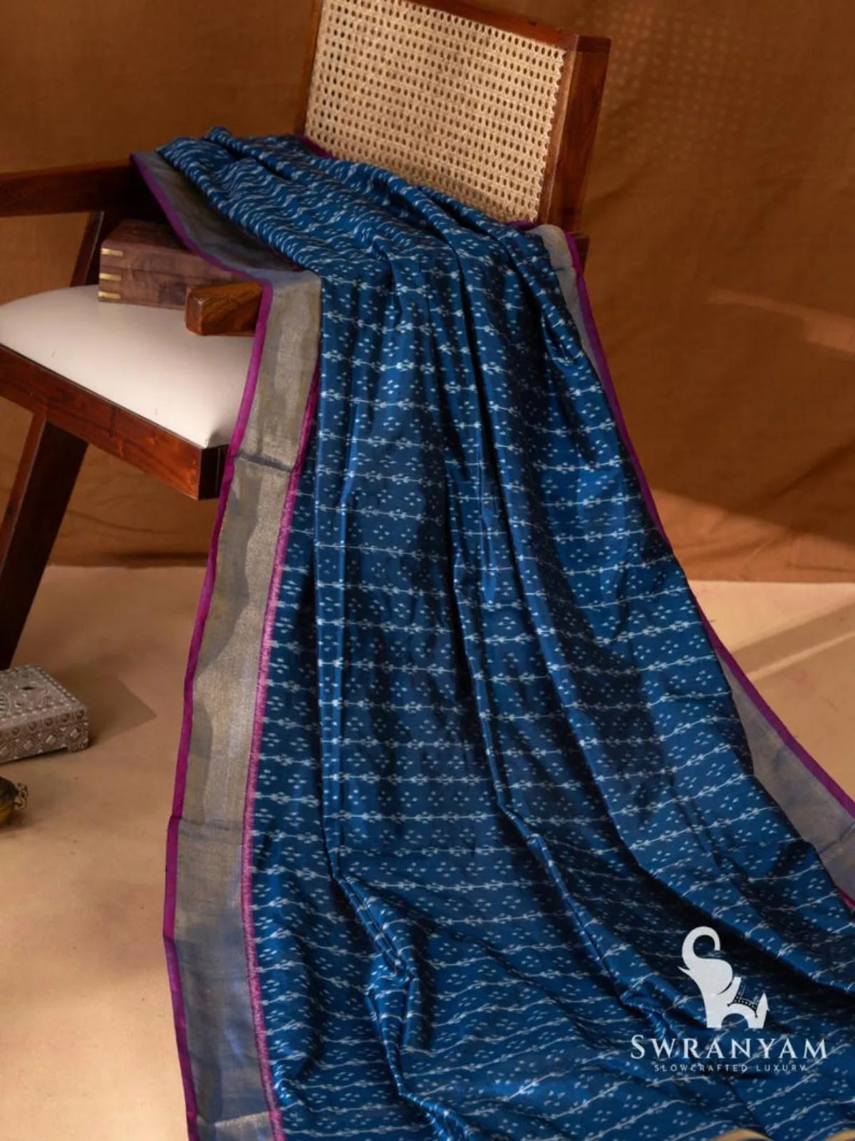 Indigo blue Pochampally ikat silk saree with rows of white ikat vine motifs and silver gold zari border on chair