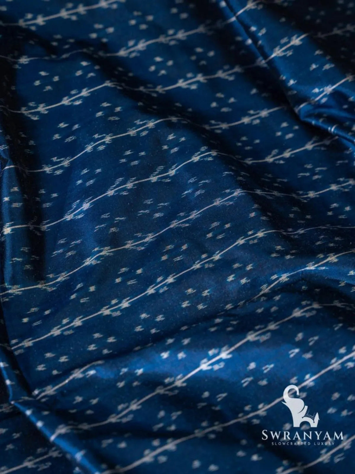 Close-up of deep blue Pochampally ikat silk with white vine and dot motifs in horizontal rows