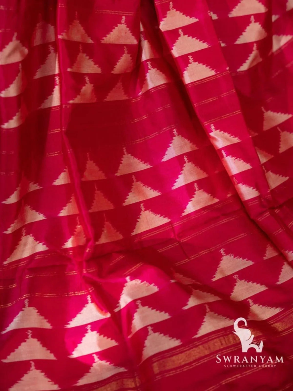 Close-up of pink silk pallu with rows of white temple triangle ikat motifs and thin gold zari lines
