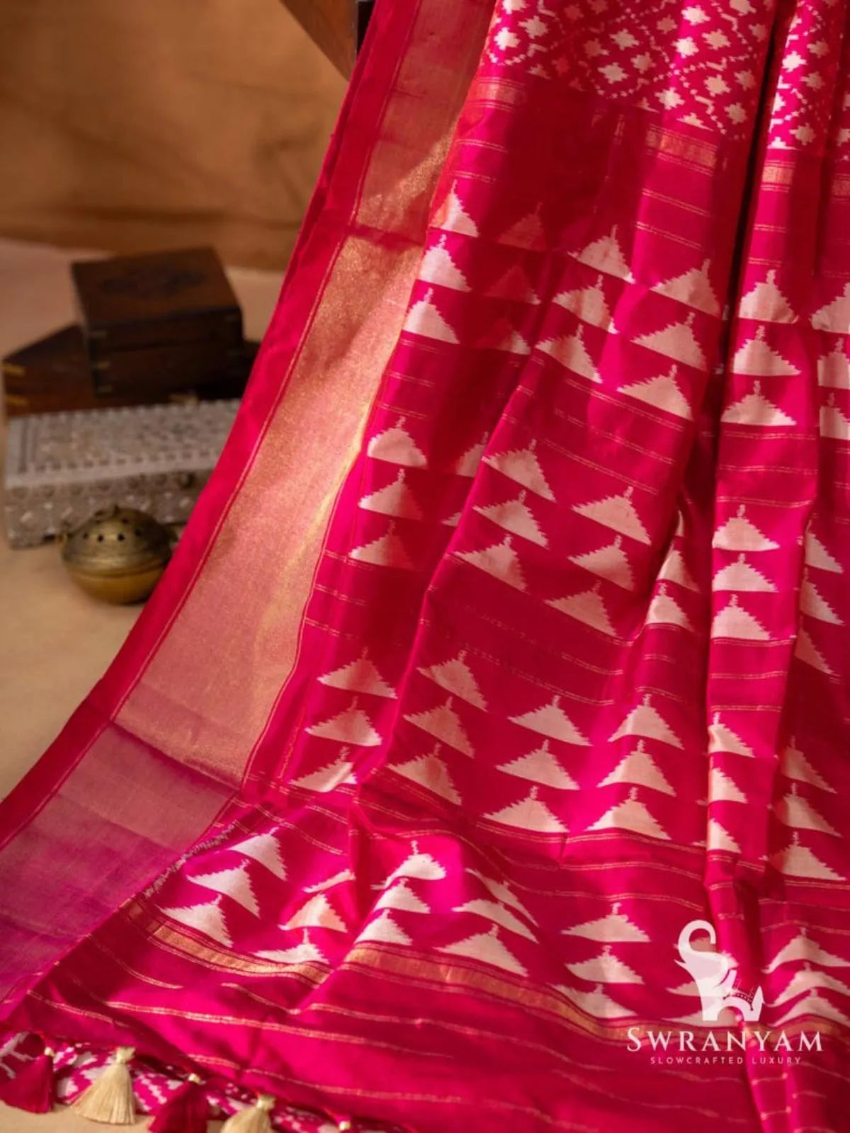 Pink pallu with white stepped temple triangle ikat motifs, gold zari stripes and pink and cream tassels