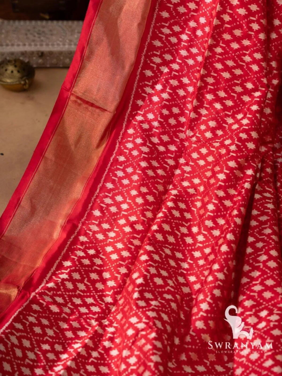 Red pallu with white stepped temple triangle ikat motifs, gold zari stripes and red and cream tassels