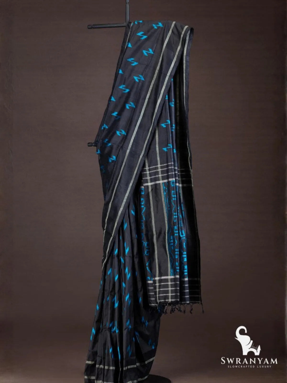 Black Pochampally ikat silk saree with blue Z-shaped ikat motifs and silver striped border draped on stand
