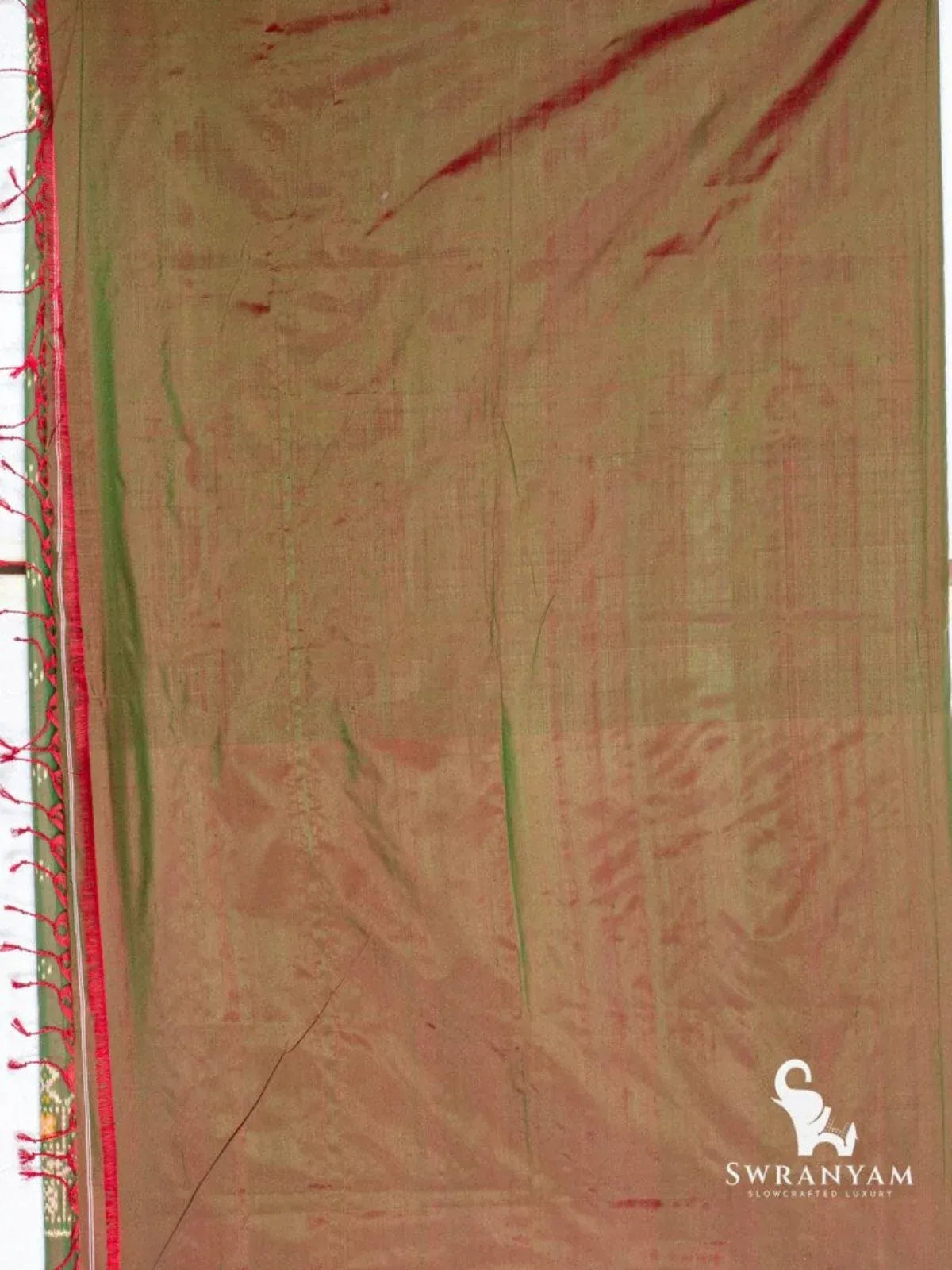 Back view of dual shade Pochampally ikat silk saree fabric showing green and maroon sheen with red tassels