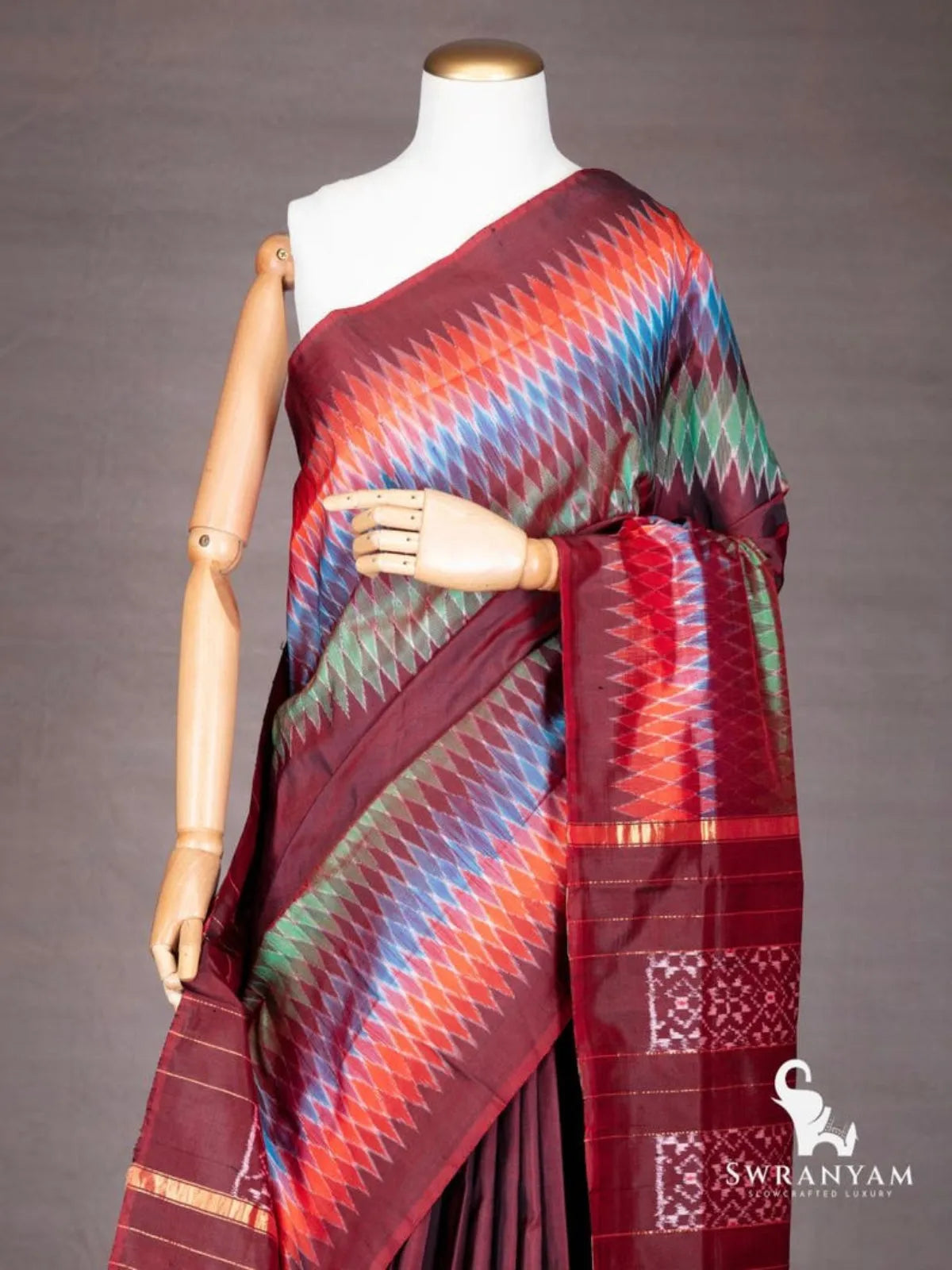 Close-up of multicolour diamond ikat border in orange, blue and green on maroon silk saree shoulder drape