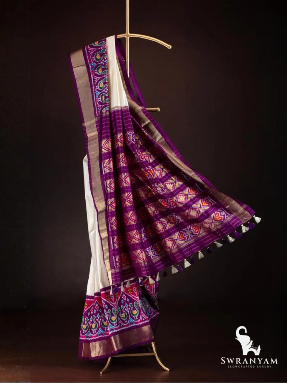 Ivory ikat silk saree with flowing purple pallu showing red and yellow diamond ikat panels, zari stripes and tassels