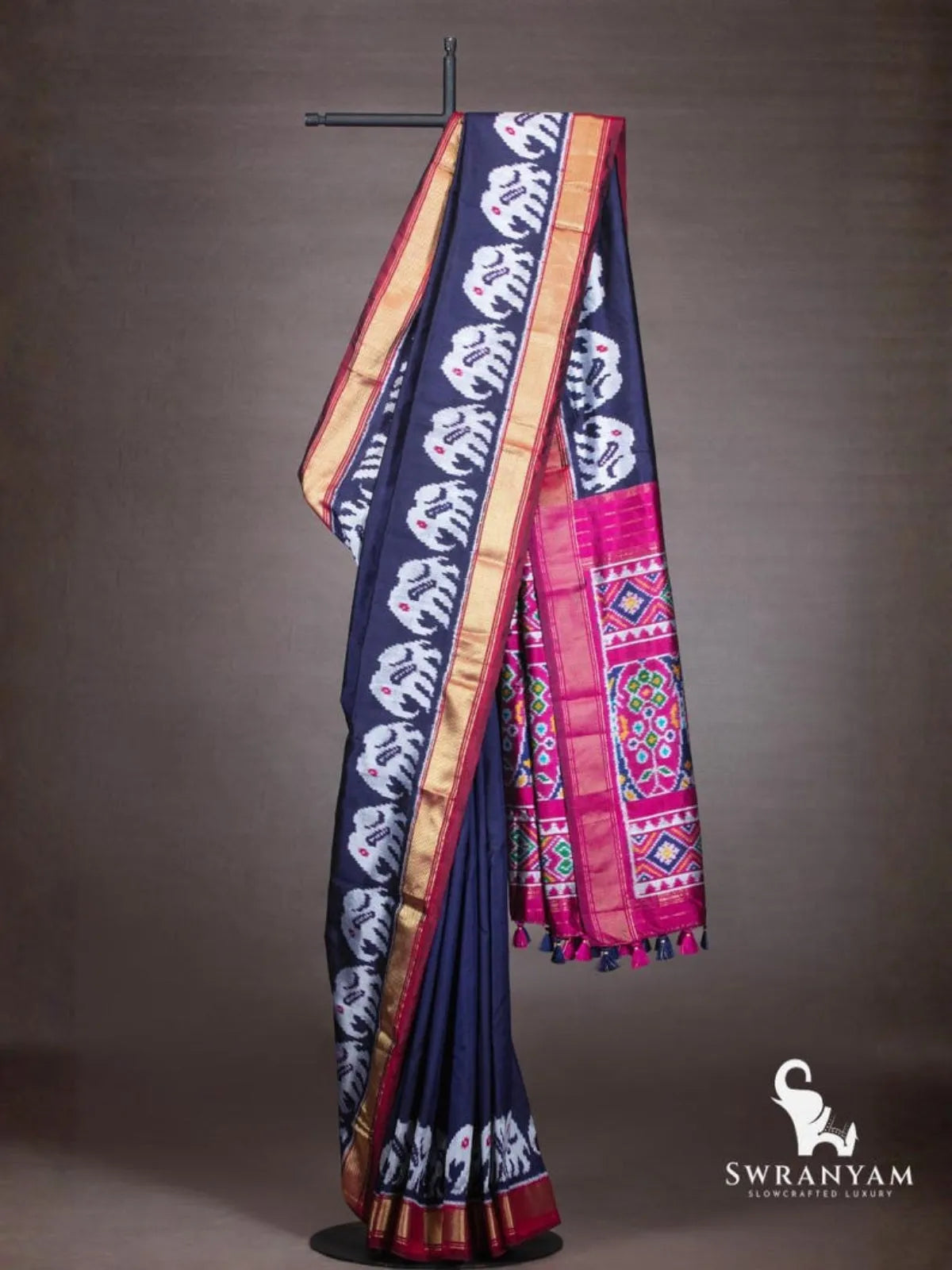 Navy blue Pochampally ikat silk saree with white elephant motifs, gold zari border and pink ikat pallu on stand