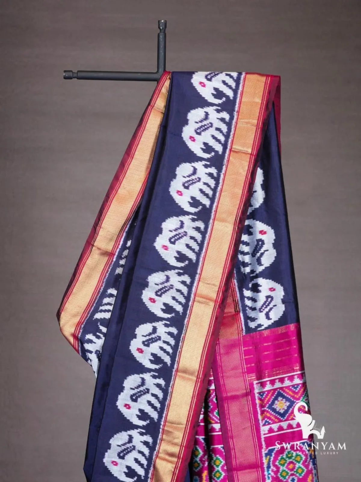 Close-up of white elephant ikat motifs on navy blue silk saree with gold zari and maroon border