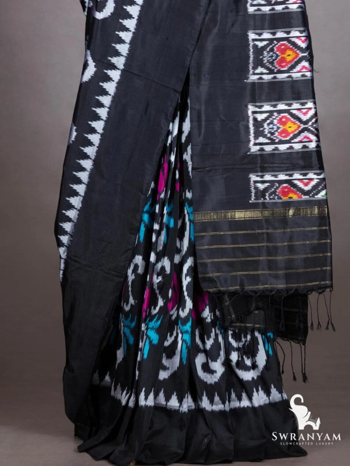 Black ikat silk saree pleats with white scroll motifs and teal accents, black pallu with heart motif ikat panels