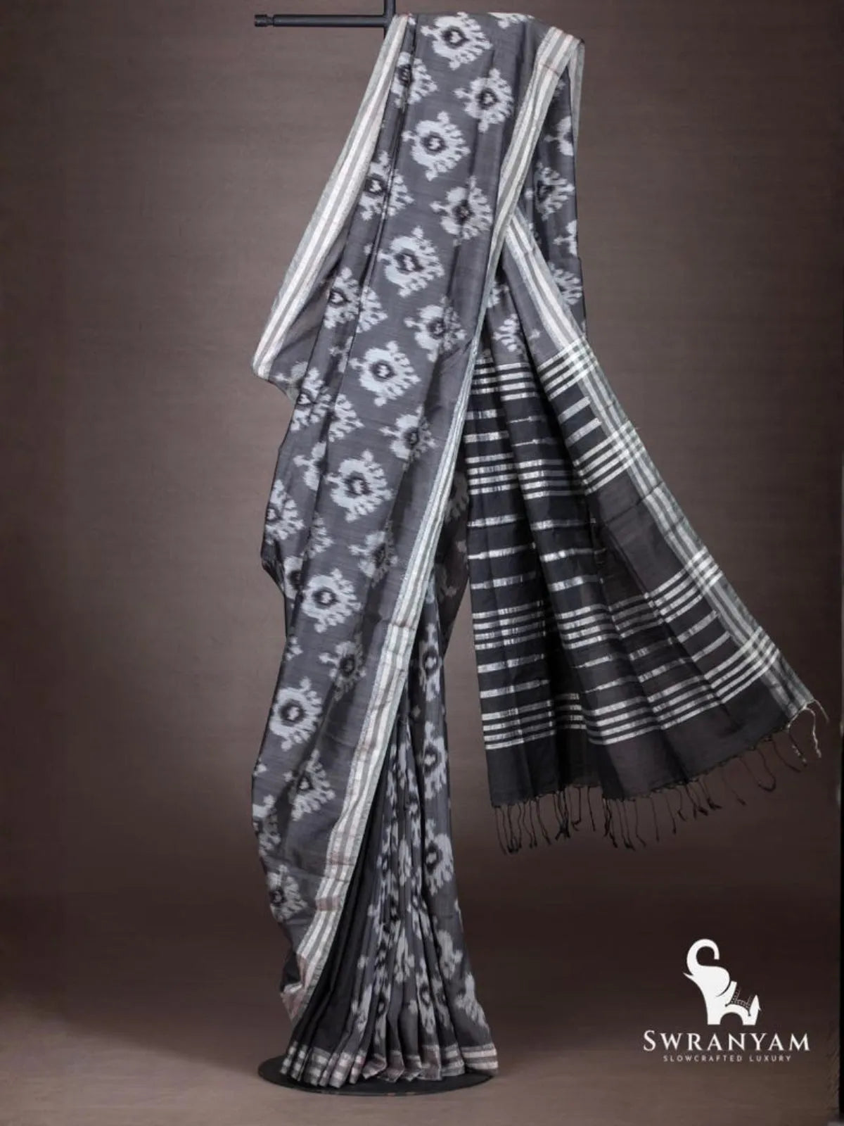 Charcoal grey ikat cotton silk saree with silver striped border and flowing black pallu with silver stripes
