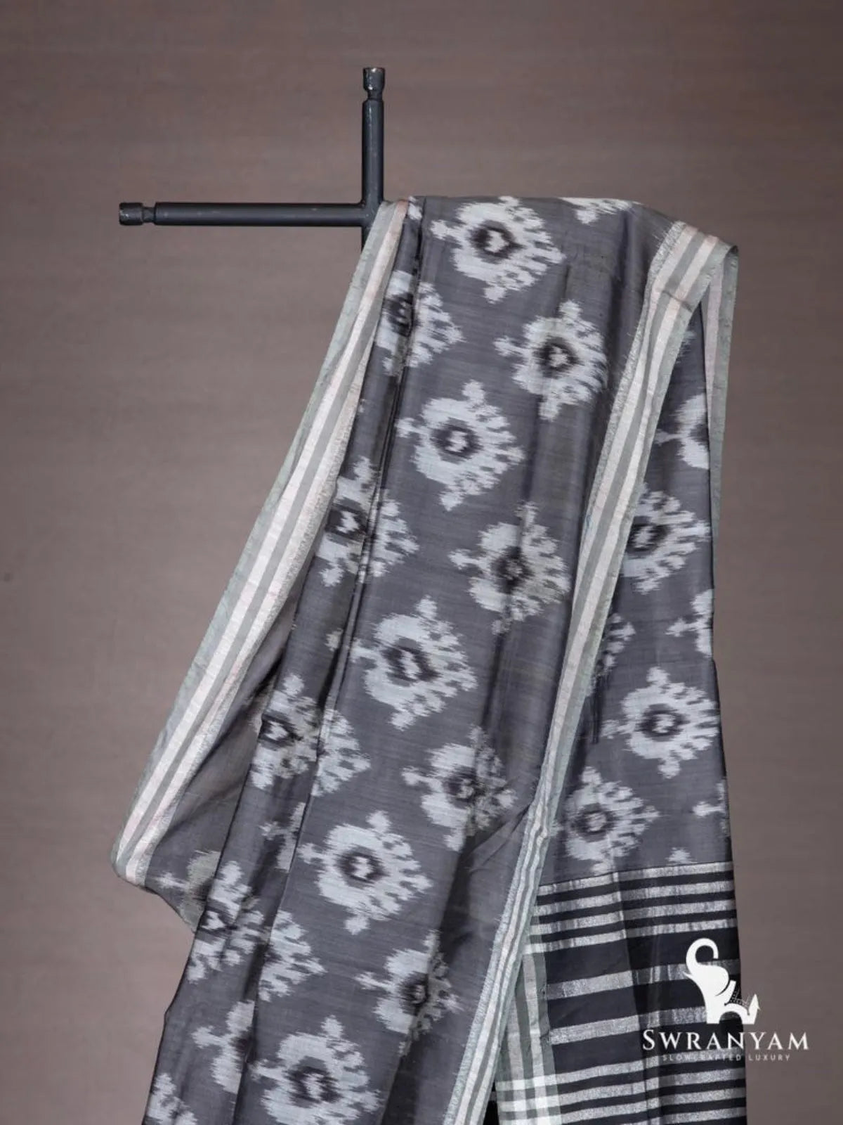 Close-up of white ikat motifs on charcoal grey cotton silk saree shoulder drape with silver striped border