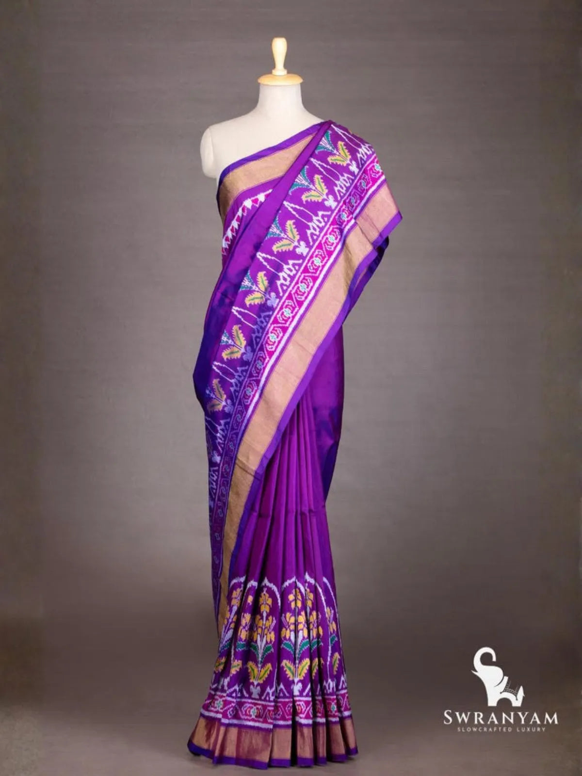 Royal purple Pochampally ikat silk saree with gold zari border and floral ikat motifs draped on mannequin, front view