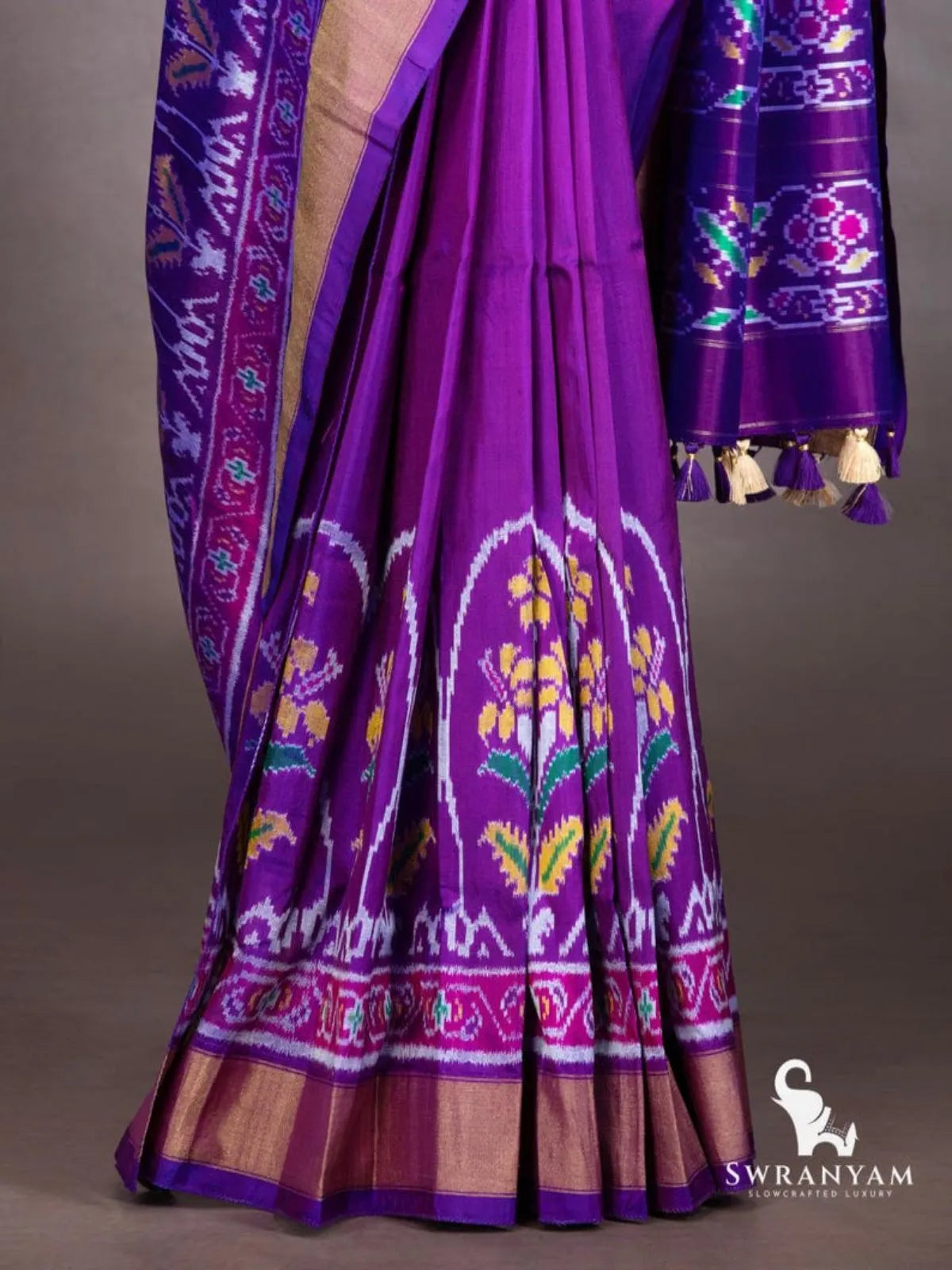 Royal purple ikat silk saree pleats with yellow and green floral ikat motifs, pink ikat border and gold zari hem