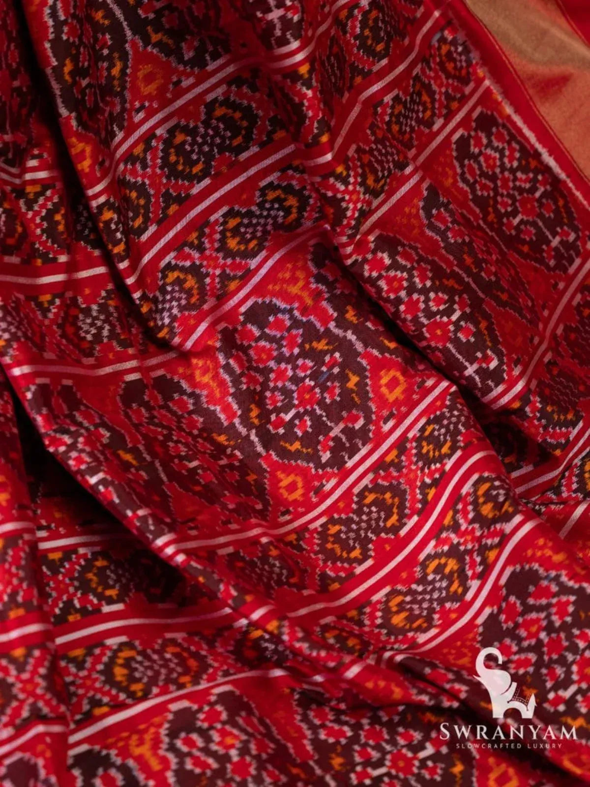 Close-up of red pallu of Pochampally ikat silk saree with maroon, orange and white woven ikat motifs