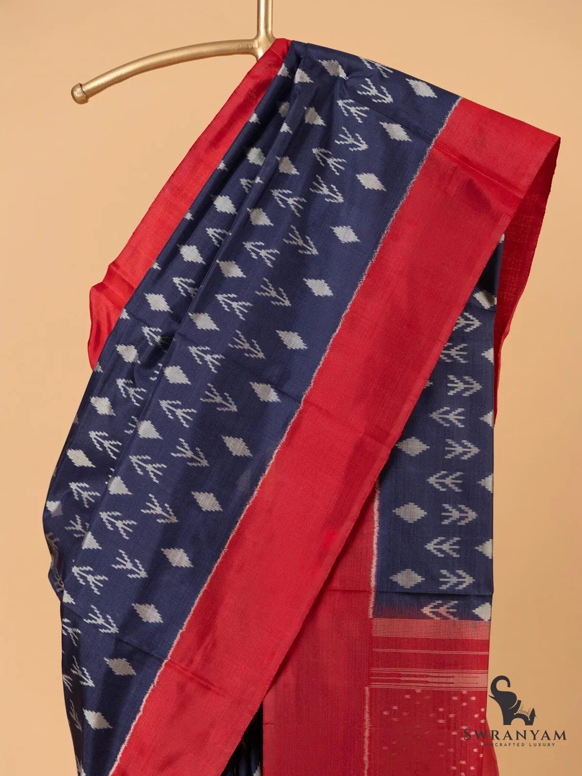 Close-up of navy blue ikat silk saree body with white diamond and arrow motifs and wide red border