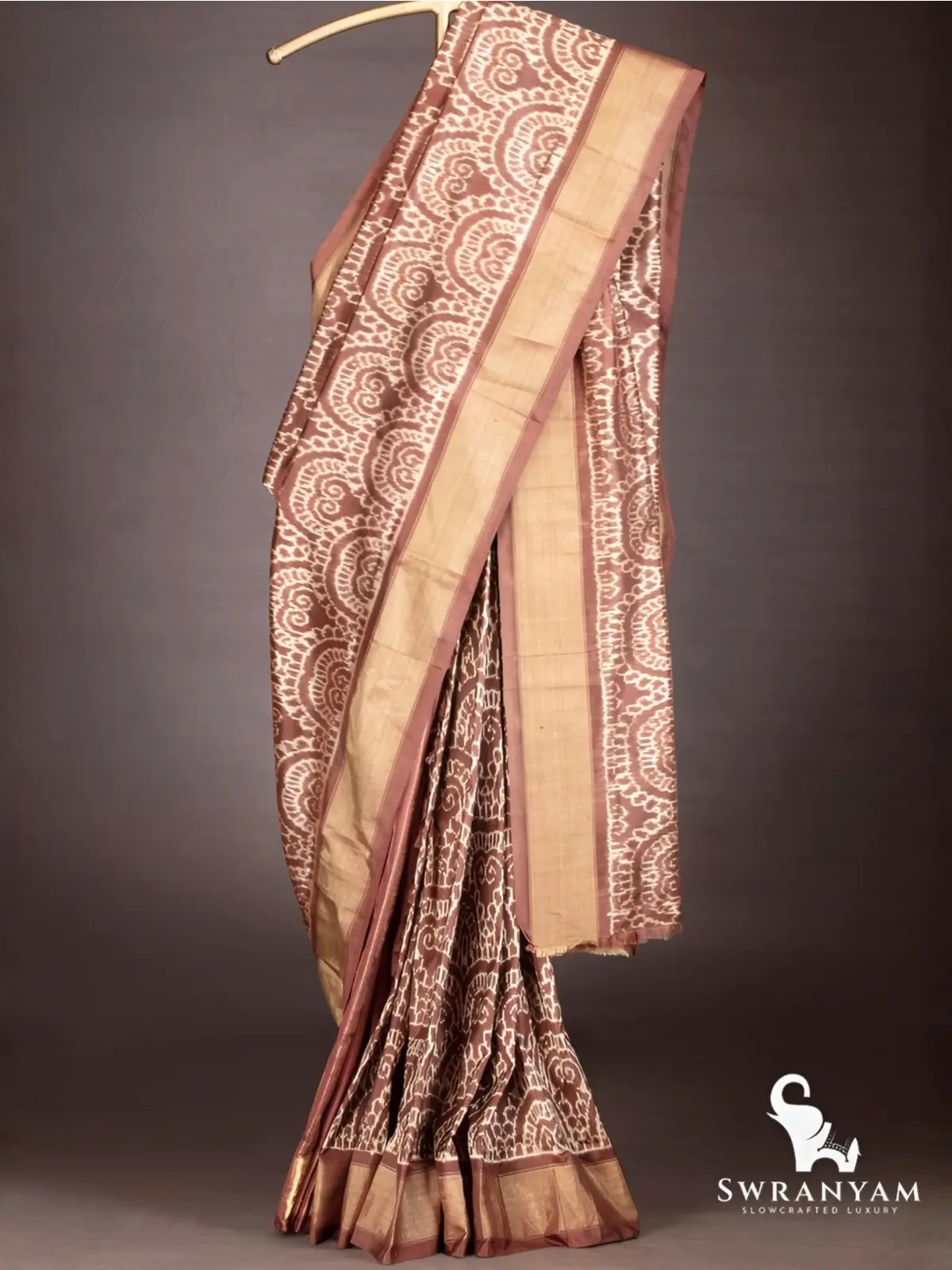 Full drape of handwoven cocoa brown ikkat silk saree showing pallu, pleats and wide antique gold border