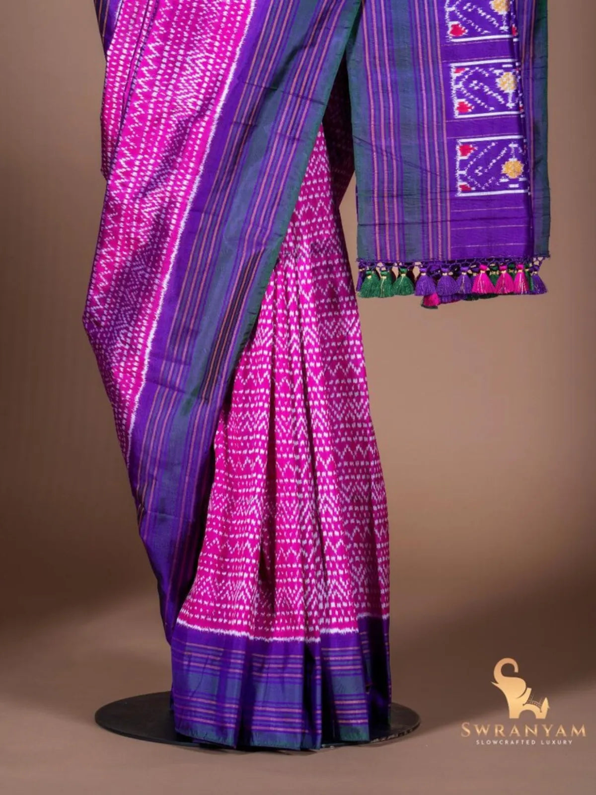 Pleats of pure pink ikat silk saree with white zigzag motifs, purple border and tasselled pallu