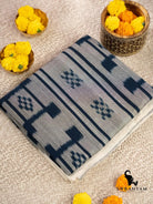Folded handwoven grey cotton ikat saree showing indigo stripes and floral ikat motifs on the body