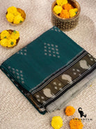 Folded emerald green Pochampally ikat cotton saree with black border and white paisley motifs beside marigold flowers