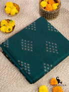 Folded handwoven emerald green cotton ikat saree showing white diamond butti motifs on the body