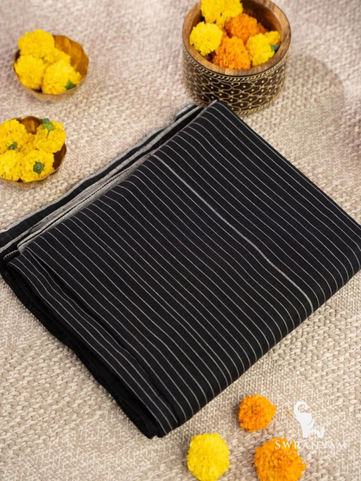 Folded handloom black cotton ikat saree showing minimal white pinstripe weave