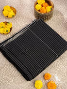Folded handloom black cotton ikat saree showing minimal white pinstripe weave