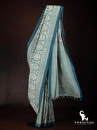 Sage green Pochampally ikat silk cotton saree with teal border and white ikat motifs draped on a stand