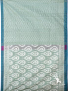 Flat lay of sage green ikat silk cotton saree showing butti body, heart motif pallu and teal border