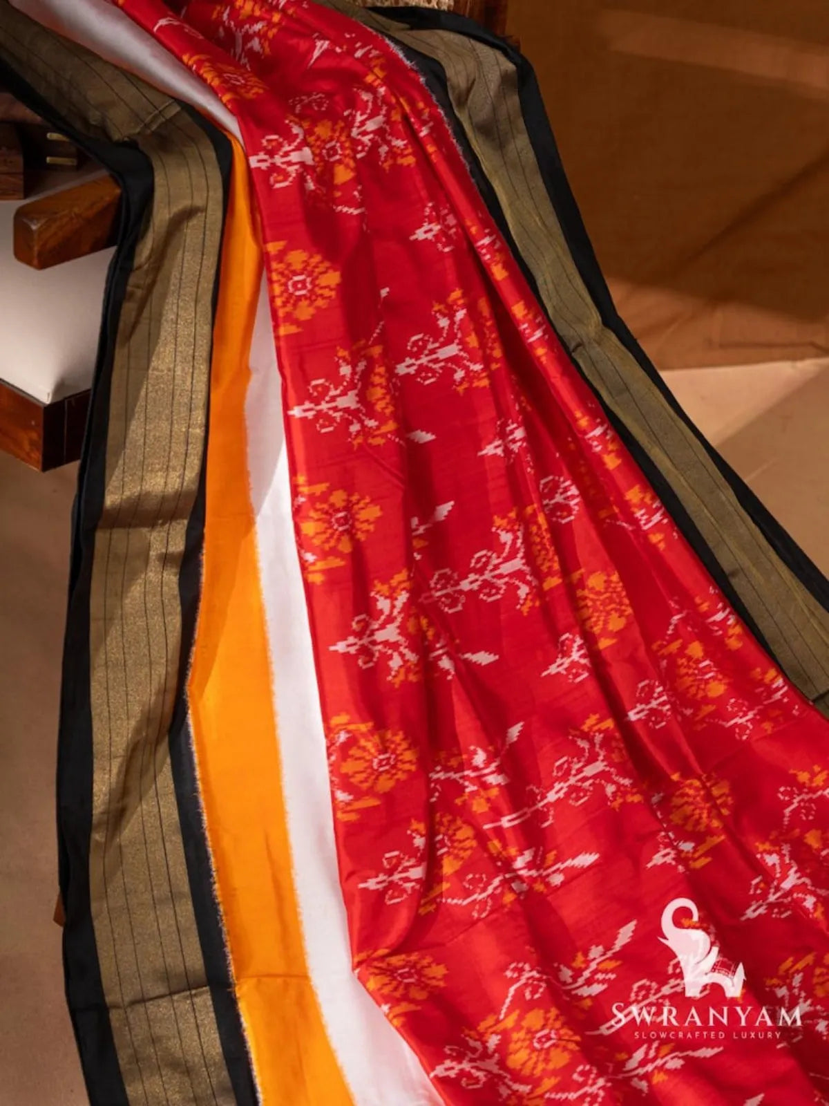 Handwoven red ikat silk saree spread diagonally showing floral ikat motifs, yellow and white panels and zari border