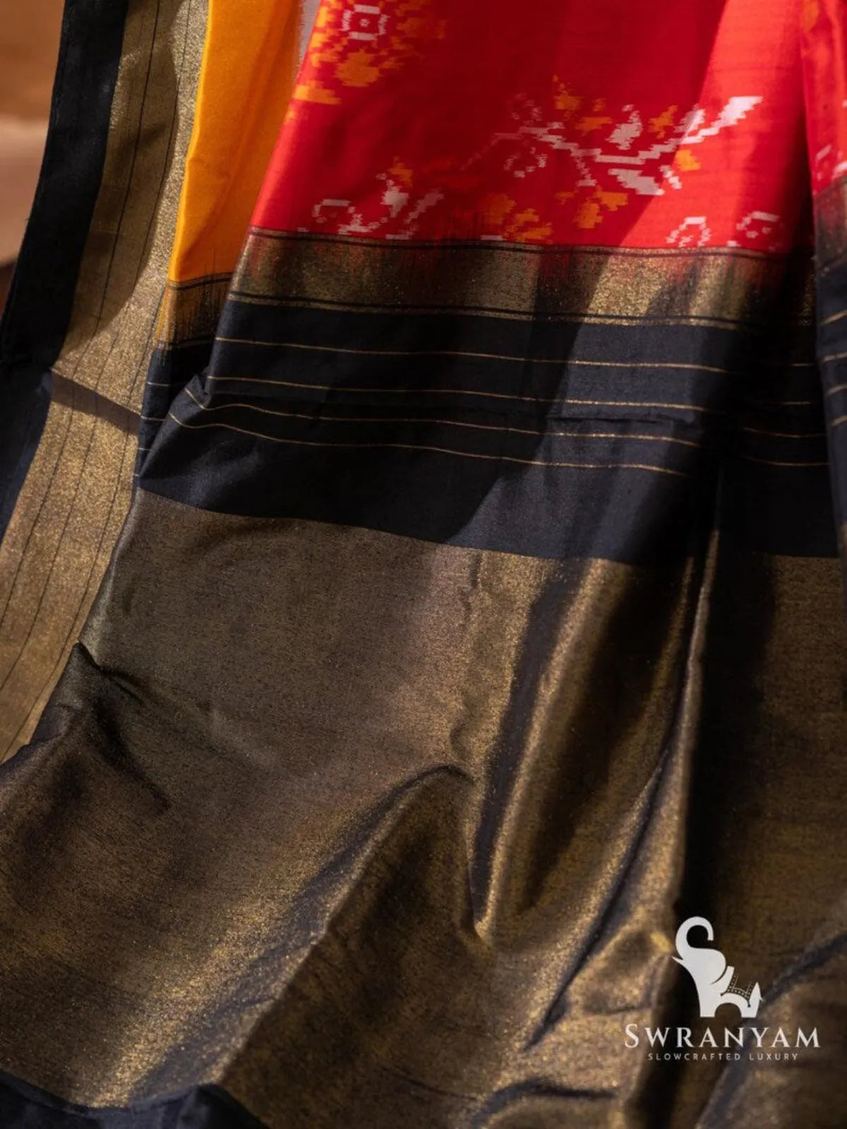 Black and golden zari pallu of red Pochampally ikat silk saree with handwoven floral ikat motifs
