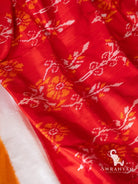 Close up of white and orange floral ikat motifs woven on the red body of Pochampally ikat silk saree