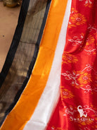 Detail of striped black zari border beside yellow and white panels of handwoven red ikat silk saree