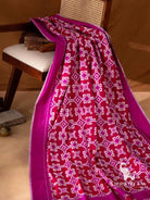 Crimson red Telia Rumal silk saree folds on chair showing white and magenta geometric double ikat motifs and magenta border