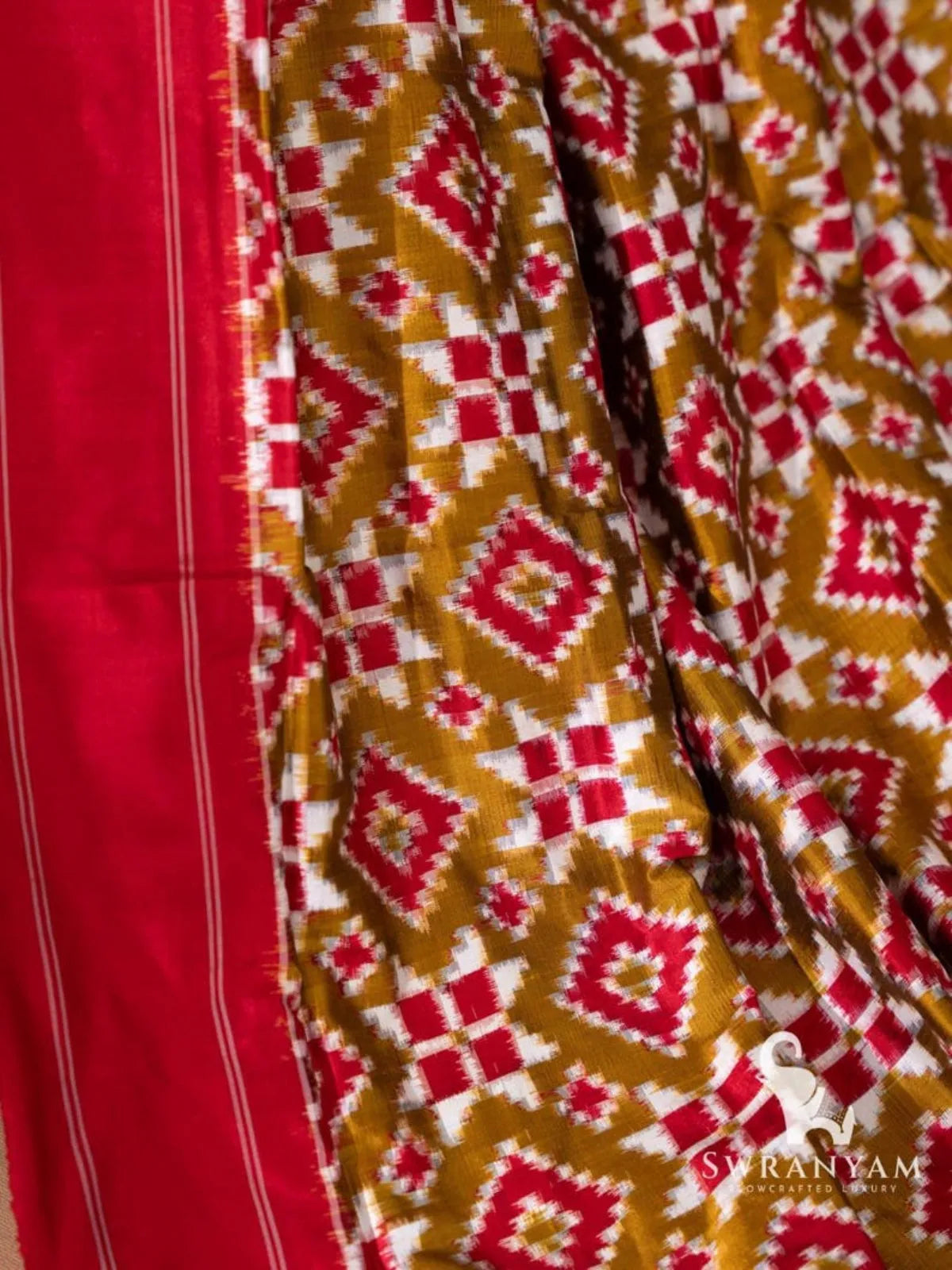 Red border with white pinstripes beside olive green Telia Rumal body with red and white diamond and star motifs