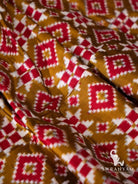 Close-up of red and white diamond and checker ikat motifs on olive green Pochampally double ikat silk fabric
