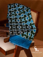 Bottle green Telia Rumal double ikat silk saree with blue and white geometric motifs and blue border folded on chair