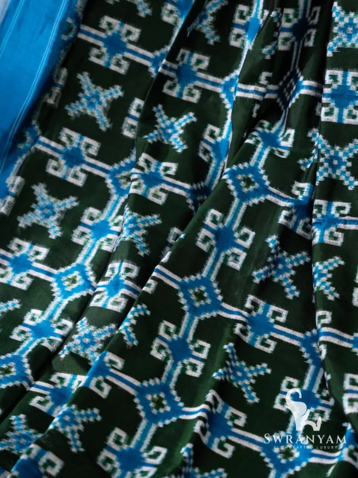 Close-up of blue and white geometric and star-shaped double ikat motifs on bottle green Pochampally silk saree