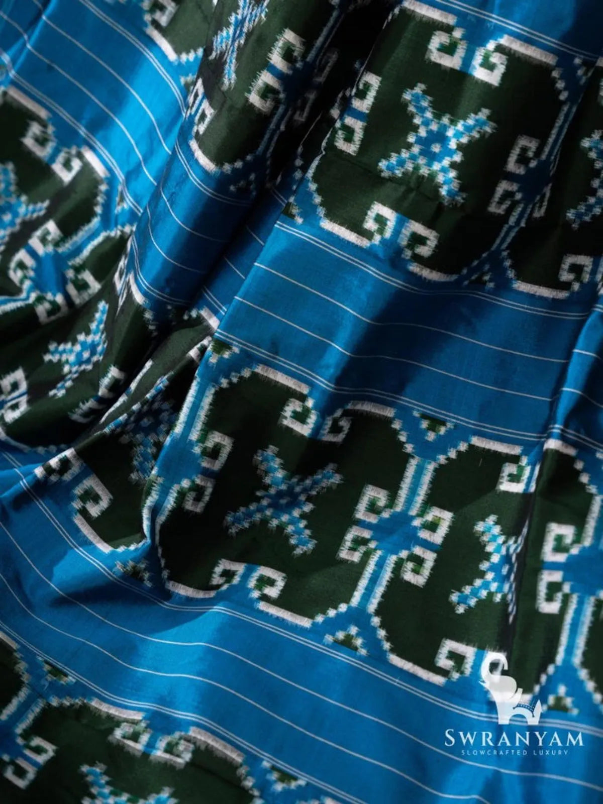 Close-up of green double ikat motif panels with blue and white details between blue pinstriped bands on pallu