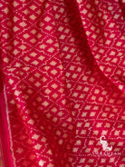 Pink silk saree folds showing rows of white geometric ikat motifs in diamond and star shapes