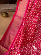 Close-up of wide gold zari border beside white geometric ikat motifs on pink Pochampally silk saree
