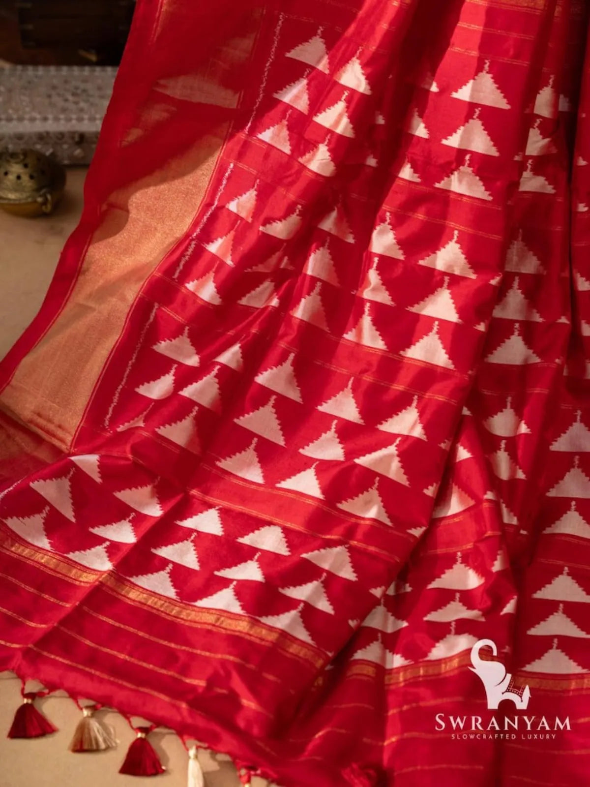 Close-up of red silk pallu with rows of white temple triangle ikat motifs and thin gold zari lines