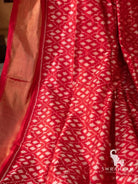 Close-up of red silk saree body with white geometric single ikat motifs beside wide gold zari border